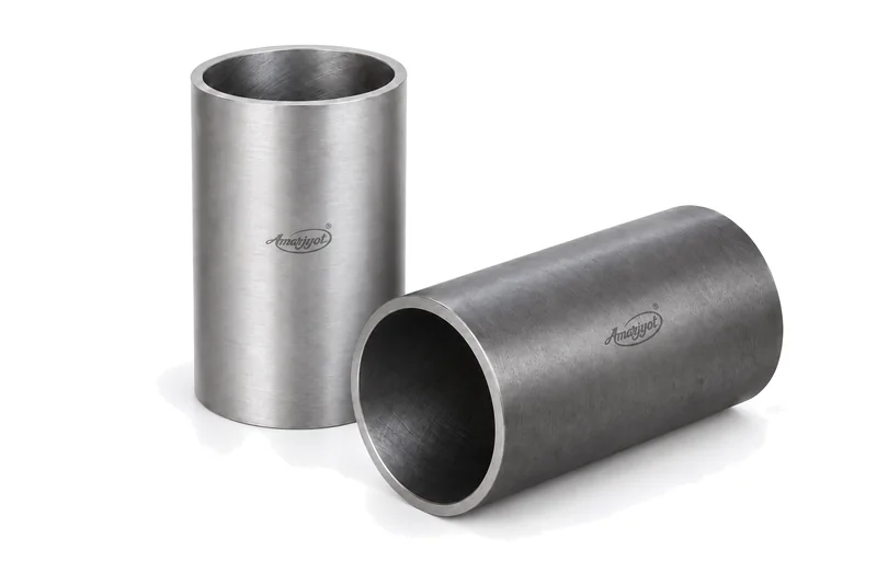 Two plain Amarjyot cylinder sleeves: one machined sleeve standing and a darker one lying in front with its open bore towards the camera